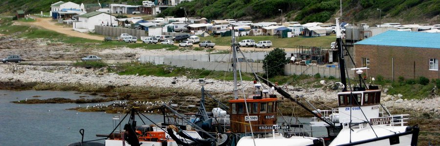 Desember kry Gansbaai se Vissermanne ‘n welverdiende blaaskans wanneer die bote herstel en opgeknap word, met ‘n vol Gansbaai Karavaanpark in die agtergrond  